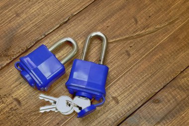 Eski ahşap arka planda, metin için boş alanı olan, anahtarla izole edilmiş mavi plastik asma kilit