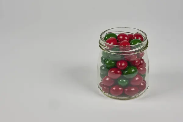 Farklı renklerde karamelaya bulanmış çikolata fıçıları, beyaz arka planda bir kabın içinde.