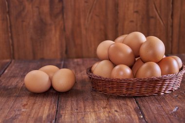Kırsal ahşap arka planı olan bir sepete yerleştirilmiş çiğ kahverengi yumurtalar.