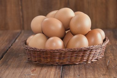 Kırsal ahşap arka planı olan bir sepete yerleştirilmiş çiğ kahverengi yumurtalar.