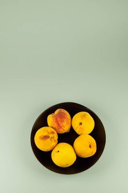 Şeftaliler yakın plan siyah bir plaka üzerinde izole edilmiş, fotokopi alanı ile hafif bir arkaplan üzerinde düzenlenmiş.