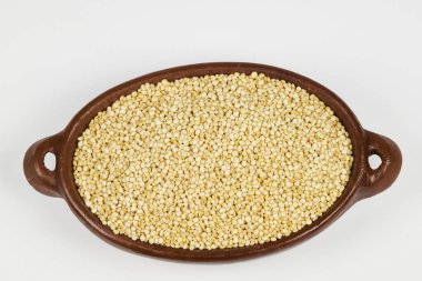 El yapımı seramik bir kabın içindeki organik kinoa tohumları (Chenopodium kinoa), beyaz arkaplan ile yakın plan fotoğraf ve kopyalama alanı