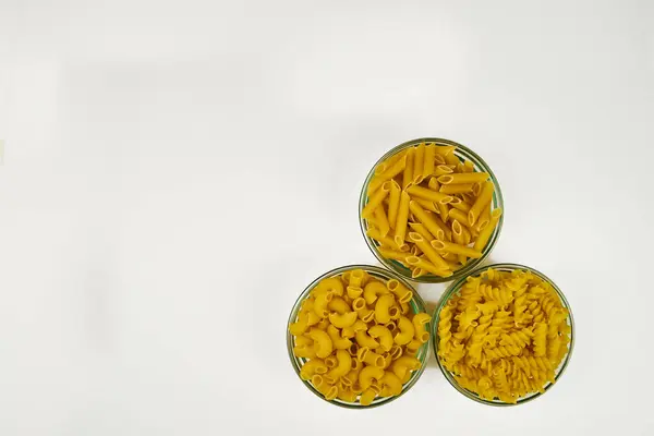 Ayrı bir karede farklı kaplarda çeşitli ham makarna türleri, beyaz arkaplanda kopyalama alanı