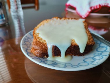 Bir dilim taze ev yapımı vanilyalı kek, üzerine yoğunlaştırılmış süt konup yenmeye hazır tatlı olarak servis edilir..