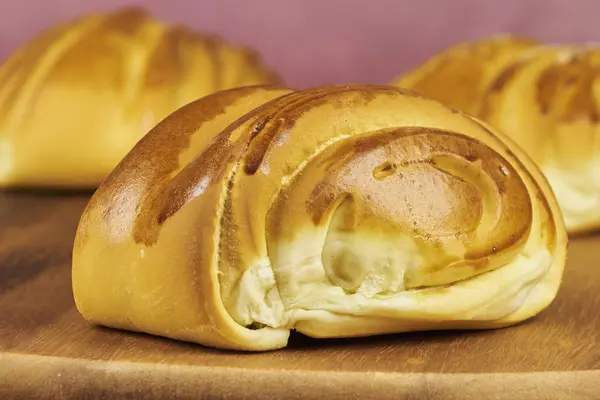 Ön planda fotokopi alanı olan ahşap bir tahtanın üzerinde yeni pişirilmiş renkli ekmek ruloları.