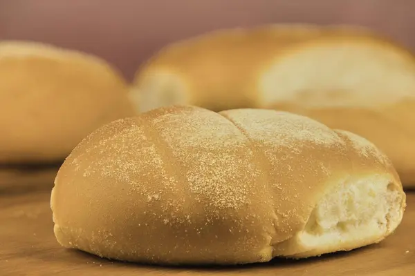 Ön planda fotokopi alanı olan ahşap bir tahtanın üzerinde yeni pişirilmiş renkli ekmek ruloları.