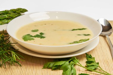 Ön planda bir kase kuşkonmaz çorbası, arka planda kırsal dekor ve fotokopi alanı olan yüksek stüdyo fotoğrafları.