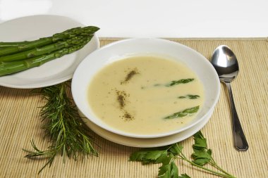 Ön planda bir kase kuşkonmaz çorbası, arka planda kırsal dekor ve fotokopi alanı olan yüksek stüdyo fotoğrafları.