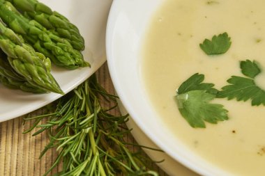 Ön planda bir kase kuşkonmaz çorbası, arka planda kırsal dekor ve fotokopi alanı olan yüksek stüdyo fotoğrafları.