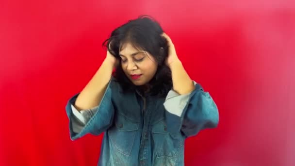 Улыбающаяся Молодая Женщина Джинсовой Рубашке Позирует Красном Фоне Игривым Жестом — стоковое видео