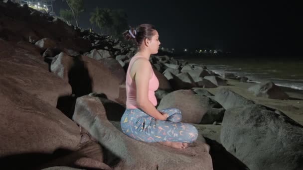 Serene Woman Meditating Rocky Beach Night Soft Lighting Tranquil Setting — Stock Video