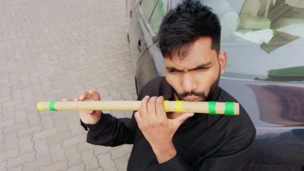男子在室外一个车辆附近演奏传统竹笛 专注于练习音乐艺术 — 图库视频影像