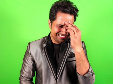 Ağlayan işadamı ve acı çektiğini ifade eden yeşil arka planla karşı karşıya.