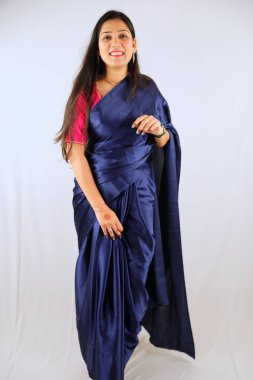 Geleneksel mavi sari giymiş gülümseyen kadın beyaz arka planda poz veriyor..