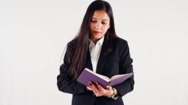 Profesyonel bir iş kadını beyaz bir arka plana odaklanmış bir ifadeyle kitap okuyor.
