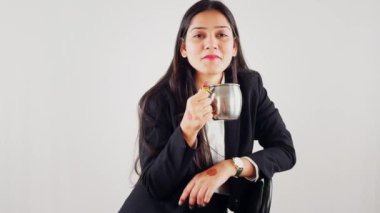 Elinde bir bardak kahve tutan gülümseyen kadın beyaz arka planda izole edilmiş günlük kıyafetler düşünüyor.