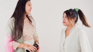Bir partide gülümseyen ve birbiriyle etkileşen iki kadın beyaz arka planda konuşan dedikoducular.