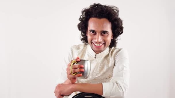 Uśmiechnięty Młody Człowiek Siedzący Kręconymi Włosami Trzymający Filiżankę Kawy Białym — Wideo stockowe
