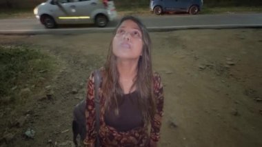Issız bir sokakta sigara içen düşünceli genç bir kadın gecenin bir yarısı ayakta dikiliyor.