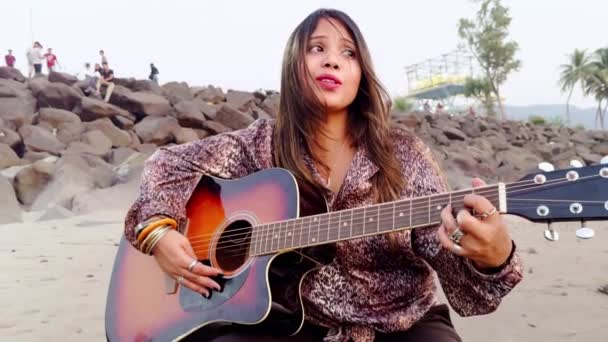 Kobieta Grająca Gitarze Piaszczystej Plaży Głębokim Wyrazem Skał Tle — Wideo stockowe