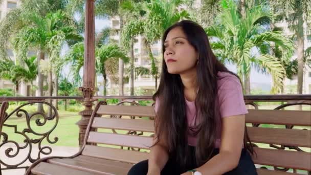 Задумчивая Молодая Женщина Сидящая Скамейке Парке Окружении Зеленых Деревьев — стоковое видео