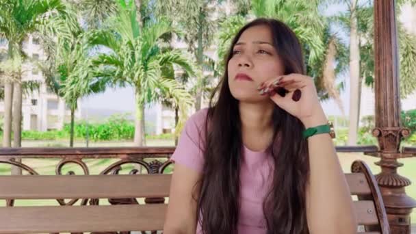Προσεκτική Νεαρή Γυναίκα Που Κάθεται Ένα Παγκάκι Περιτριγυρισμένη Από Πράσινα — Αρχείο Βίντεο