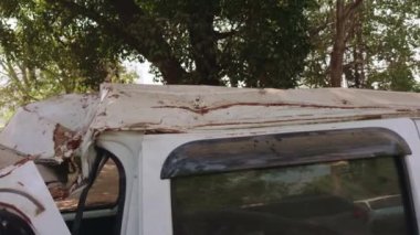 Şiddetli çatısı ve gövdesi hasar görmüş bir beyaz minibüs bir trafik kazası sonrası oluşan bir kazayı resmediyor.