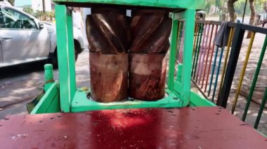 Sokak arabasında geleneksel şeker kamışı suyu sökücü. Ahşap variller ve görülebilir ezilmiş kamışlarla birlikte. Asya sokak yemekleri.
