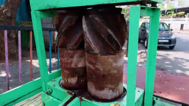木製のドラムが付いている通りのカートの伝統的なサトウキビジュースの抽出器は目に見える インドのアジアの通り食糧を粉砕しました — ストック動画