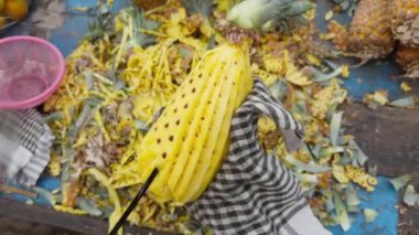 Sokak satıcıları renkli bir meyve tezgahında ananas soyarken ve keserken usta bir şekilde sokakta meyve satarken... 