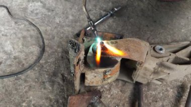 Metal atölyedeki tezgahta dururken kaynak makinesinin elinde kıvılcımlar uçuşuyor.