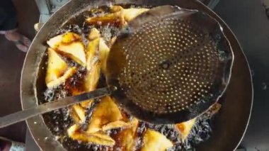 Yağlı bir tavada kızarmış samosa. Sokakta geleneksel Hint mutfağı konseptini koruyor. Hint yemekleri.