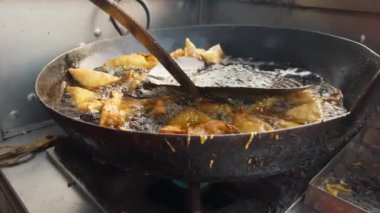 Yağlı bir tavada kızarmış samosa. Sokakta geleneksel Hint mutfağı konseptini koruyor. Hint yemekleri.