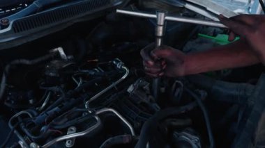Tamirci ellerinin, alacakaranlıkta araç gereçleri ile araba motorunu tamir etmesini kapat.