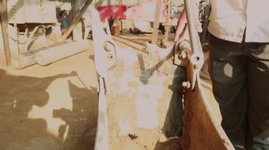 Kazı işçisi, kazıcının kırık dişlerinin olduğu yerdeki İngiliz anahtarının yardımıyla bir kazıcı toprak kova dişini tamir ediyor.