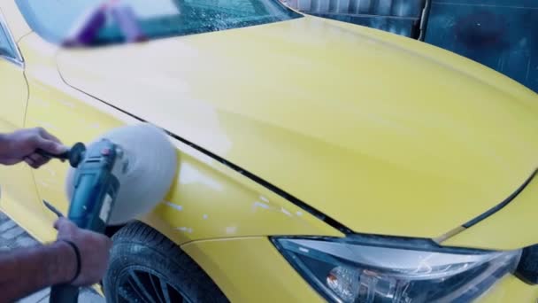 研修会の摩擦で磨く車の外装車を詳述する電気緩衝が付いている黄色い車を磨く人の近く — ストック動画