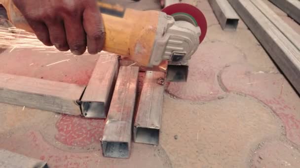 製造工場でグリルを作るスパークで金属にアングルグラインダーを使用して労働者の手を閉じる — ストック動画