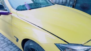 Dıştaki elektrikli tampon ile sarı bir arabayı cilalayan birinin fotoğrafını çek.
