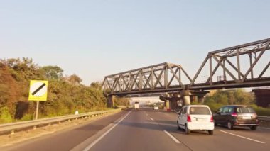 Büyük çelik köprü yapısının altında güneşli bir günde aşağıdan geçen araçlar otoyolda ya da otobanda, Asya, Hindistan 'da ilerliyor. 