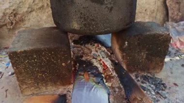 Kırsal ortamlarda, Asya ve Hindistan 'da kaynar su pişirmek için kullanılan yakacak odunuyla derme çatma bir sobada geleneksel toprak tenceresi.     