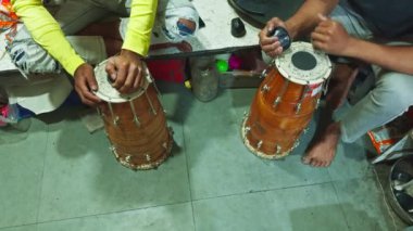 Geleneksel bir davulu karışık bir masada akort eden insanlar ellere ve enstrüman tamircisine odaklanıyorlar. Asya, Hindistan 'daki müzik atölyesinde davul tamir ediyorlar. 