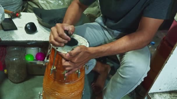 ミュージカルワークショップ アジア インドでドラムを修理する手と器具に焦点を当てたテーブルに伝統的なドラムをチューニング — ストック動画