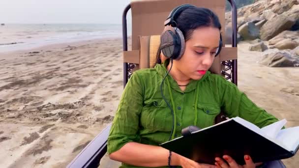 배경에 바위와 모래와 의자에 헤드폰을 해변에 집중된 — 비디오