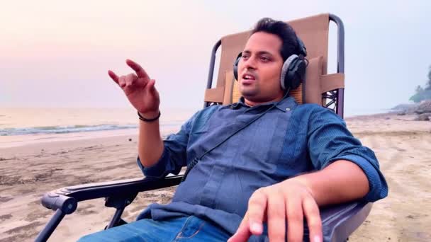 Mężczyzna Relaksujący Się Krześle Plażowym Słuchający Muzyki Słuchawkami Zamkniętymi Oczami — Wideo stockowe