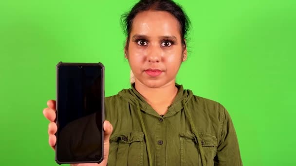 デジタルモックアップに最適なグリーンバックグラウンドの空白の画面でスマートフォンを提示する自信のある女性 — ストック動画