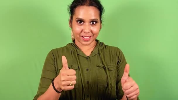 カジュアルな緑のシャツを着た緑色のスクリーンの前に親指を与える自信のある女性を笑う — ストック動画