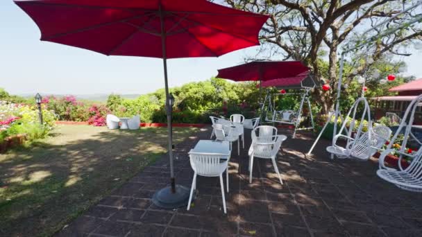Kawiarnia Ogrodowa Świeżym Powietrzu Czerwonymi Parasolami Białymi Krzesłami Bujną Zielenią — Wideo stockowe