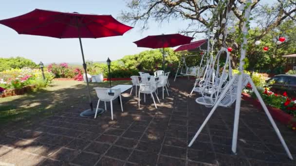 Gartencafé Freien Mit Roten Sonnenschirmen Weißen Stühlen Und Üppigem Grün — Stockvideo