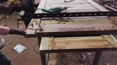 Marangoz, Asya ve Hindistan 'da aletlerin etrafa saçıldığı bir atölyedeki ahşap kalaslara kelepçe takıyor. 