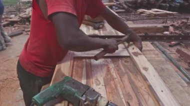 Asya ve Hindistan 'daki atölyede aletlerle ahşap tahtalar üzerinde çalışan bir marangozun yakın çekimi.  